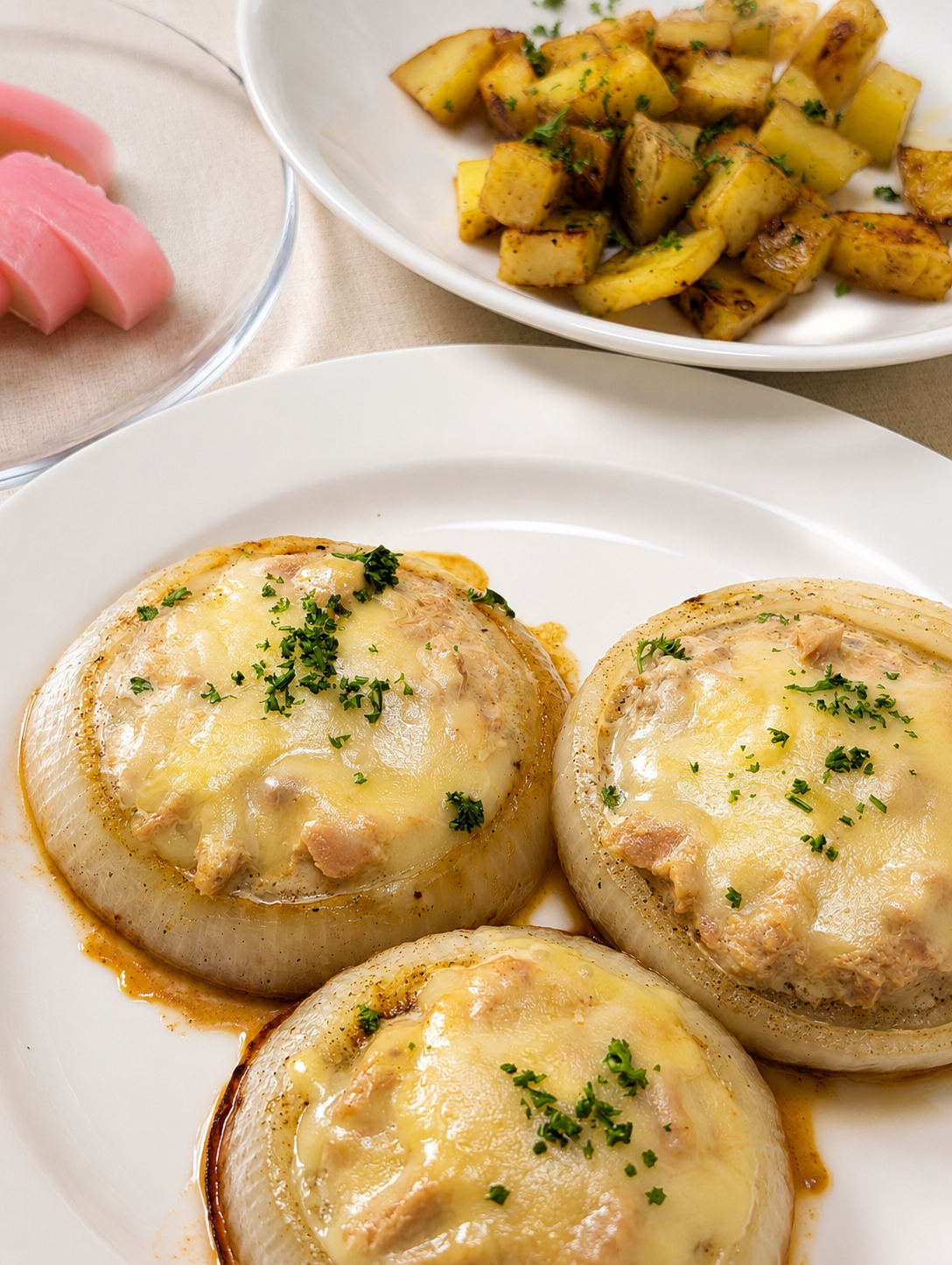 オニオンステーキのツナマヨチーズ焼きと、ハーブを散らしたコロコロポテト（ChatGPTで加工）