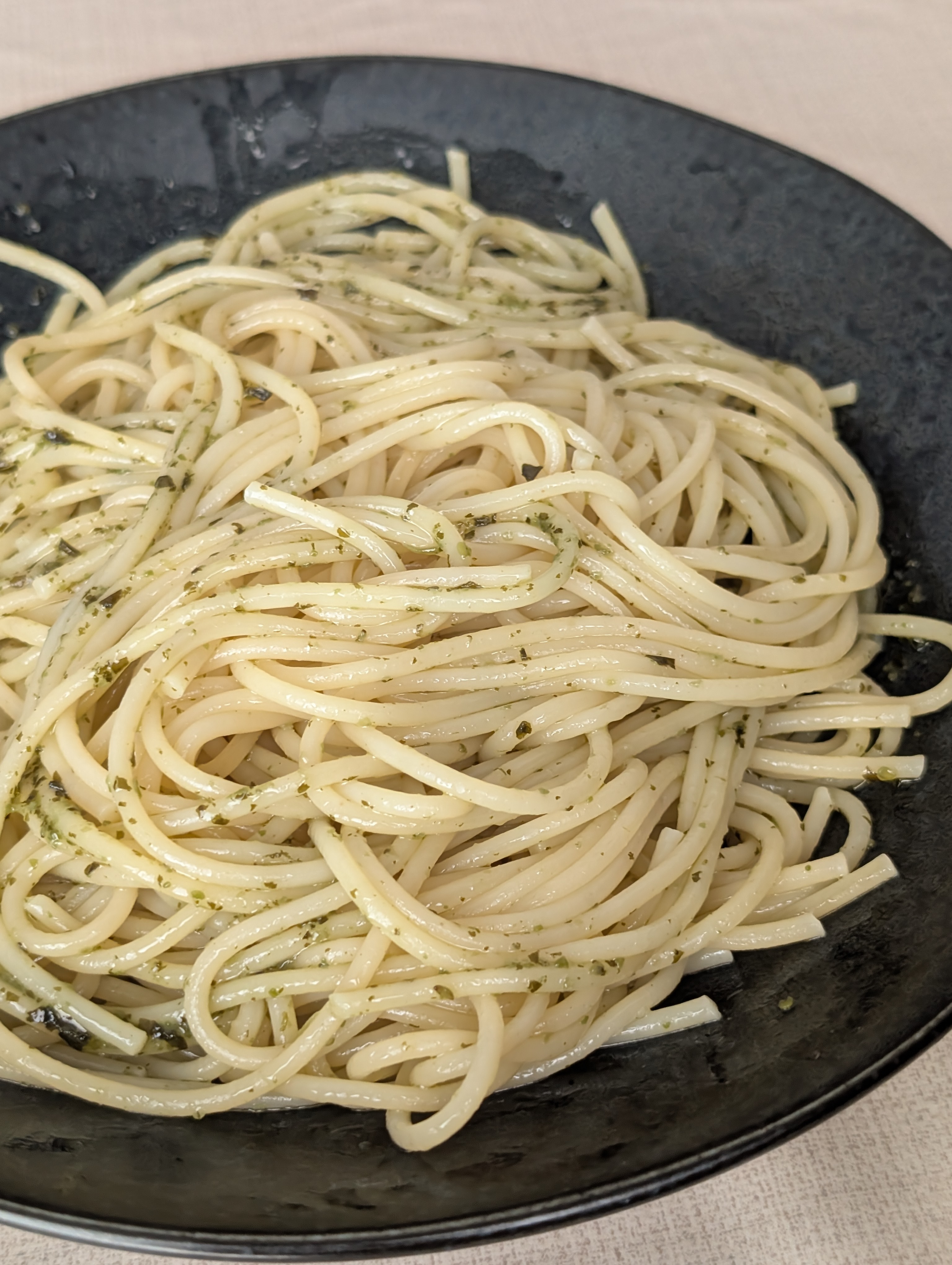 黒い皿に盛られたバジルソースのスパゲッティ