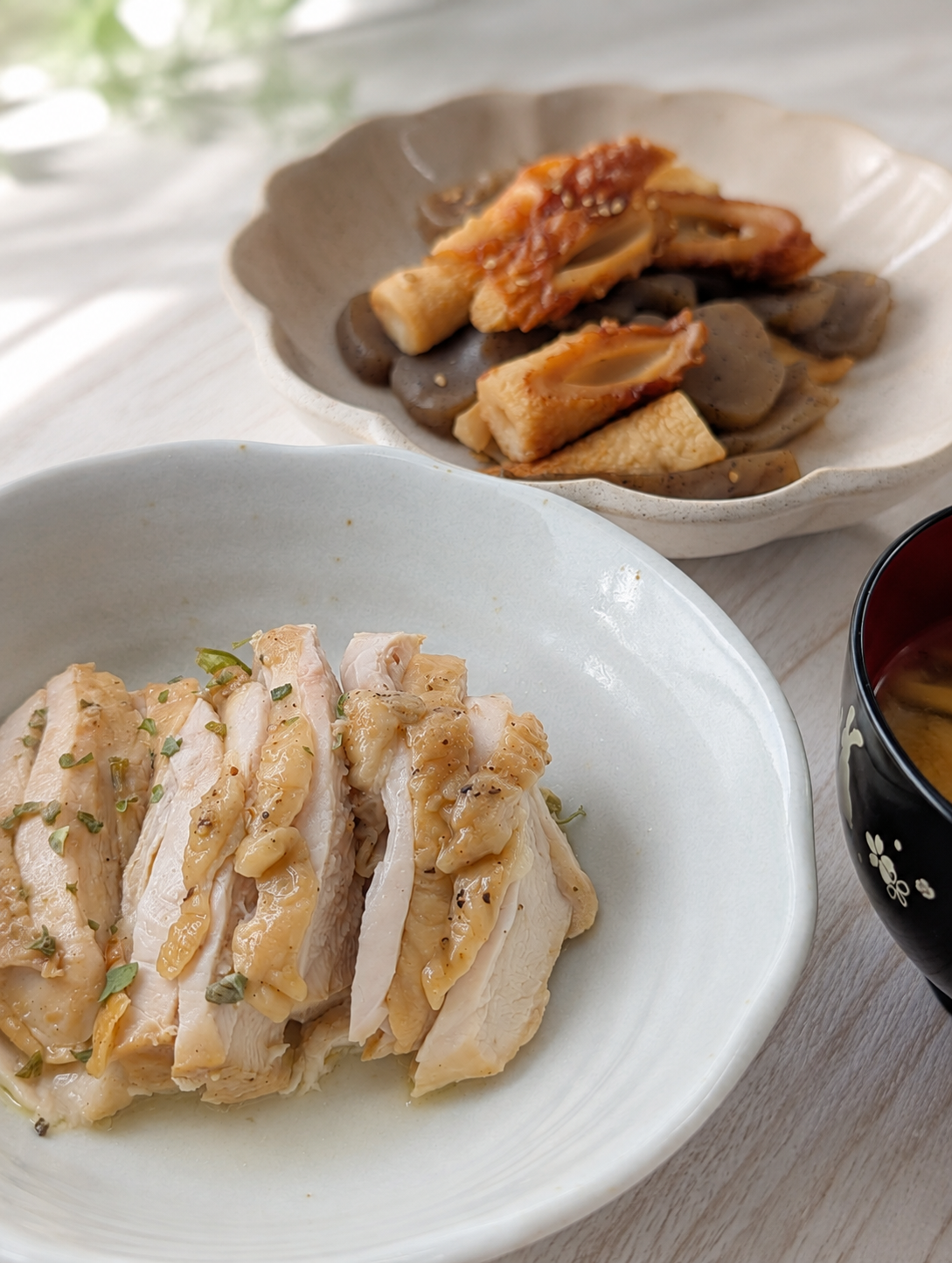 白い皿に盛った蒸し鶏と、奥の小鉢のちくわとこんにゃくの煮物