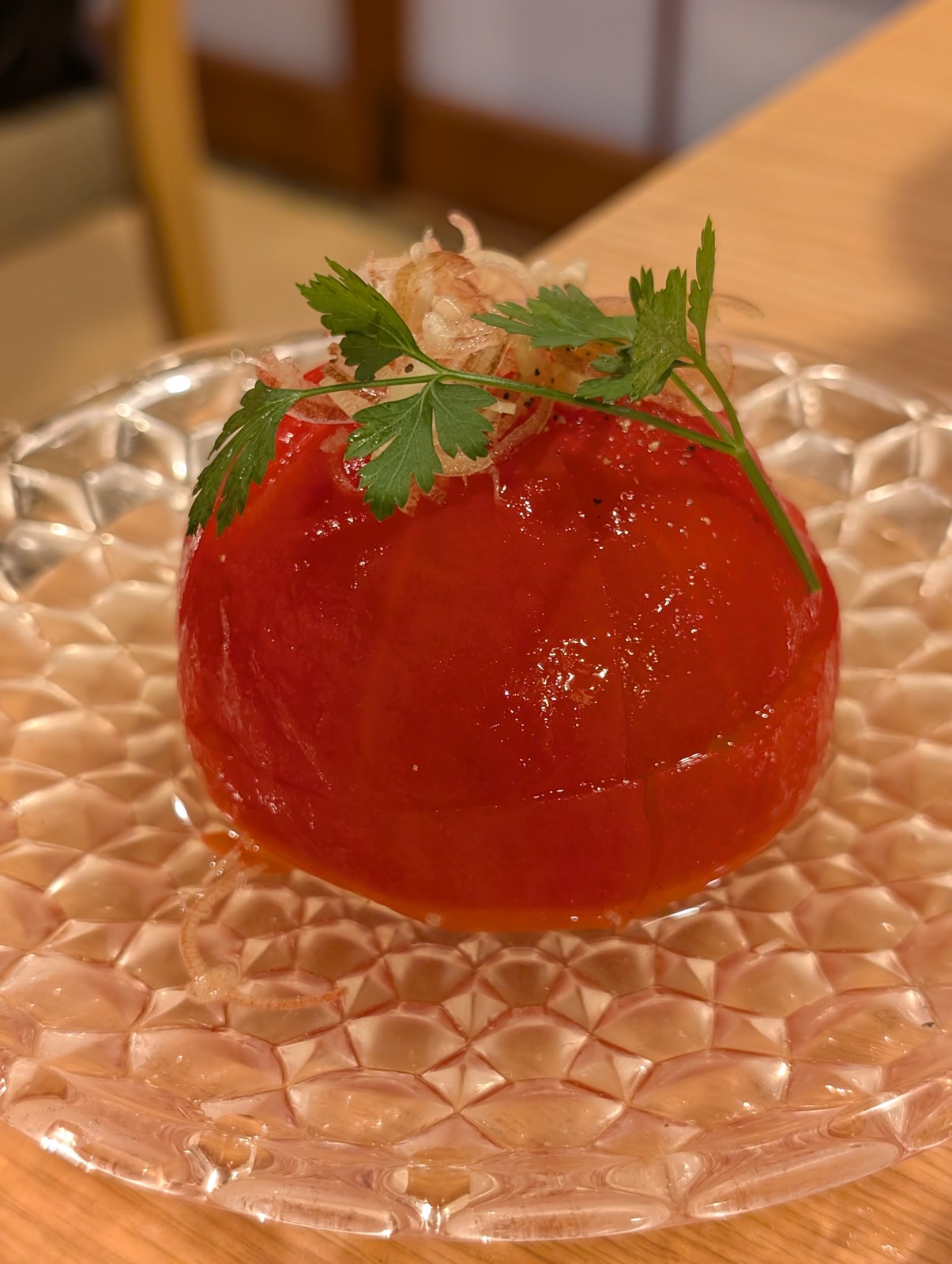 ガラスの器に盛られた皮むきトマトの冷菜。みょうがと三つ葉が上にのっている