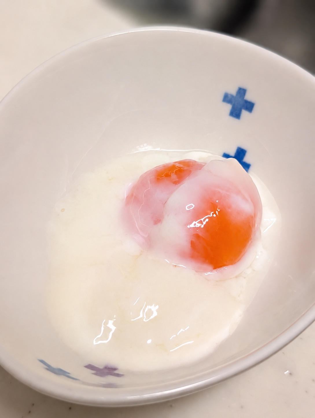 青いクロス柄の茶碗に割り入れた温泉卵