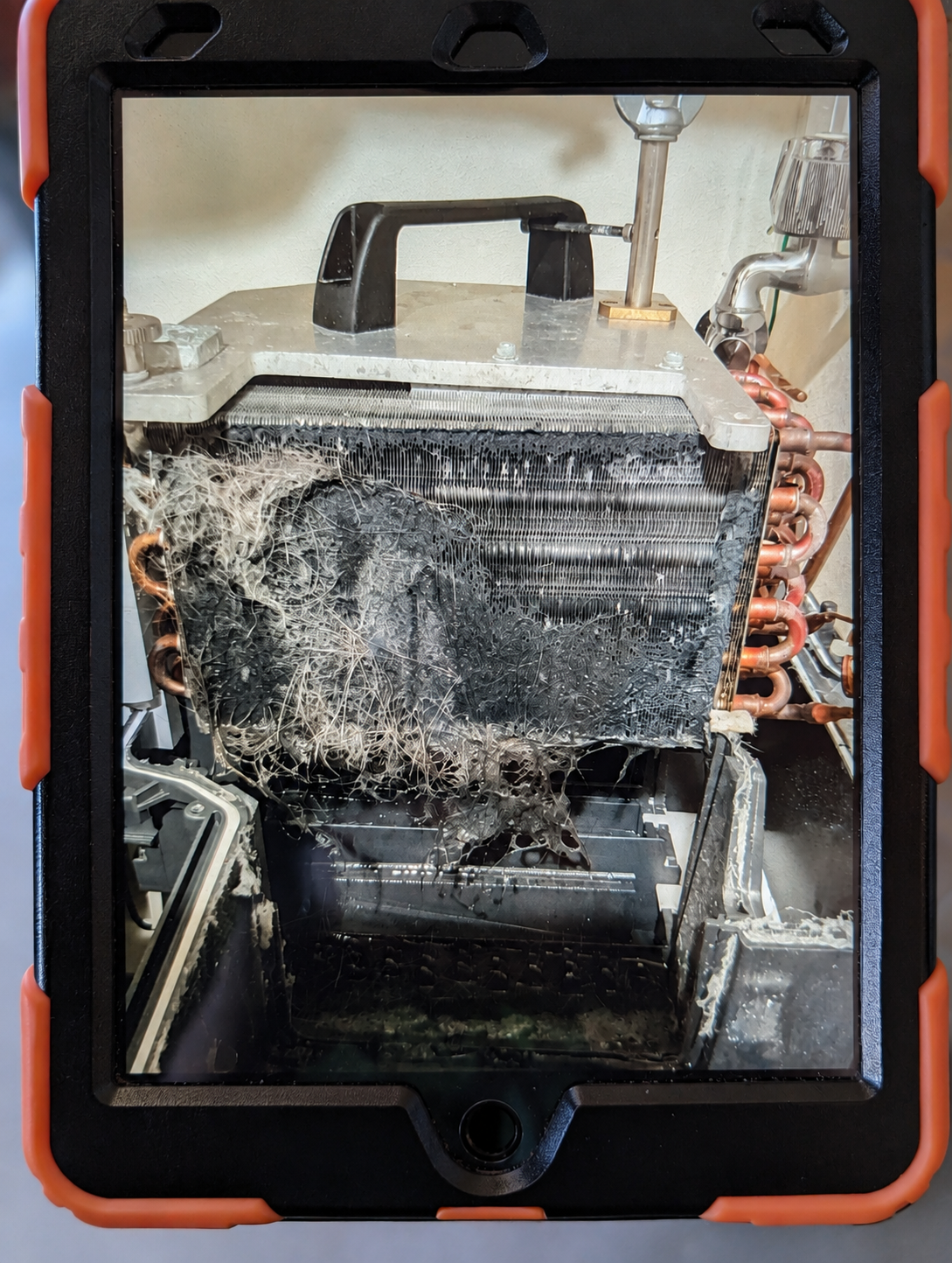 タブレットの画面に映る、猫の毛がびっしり詰まった洗濯機のヒートポンプユニット