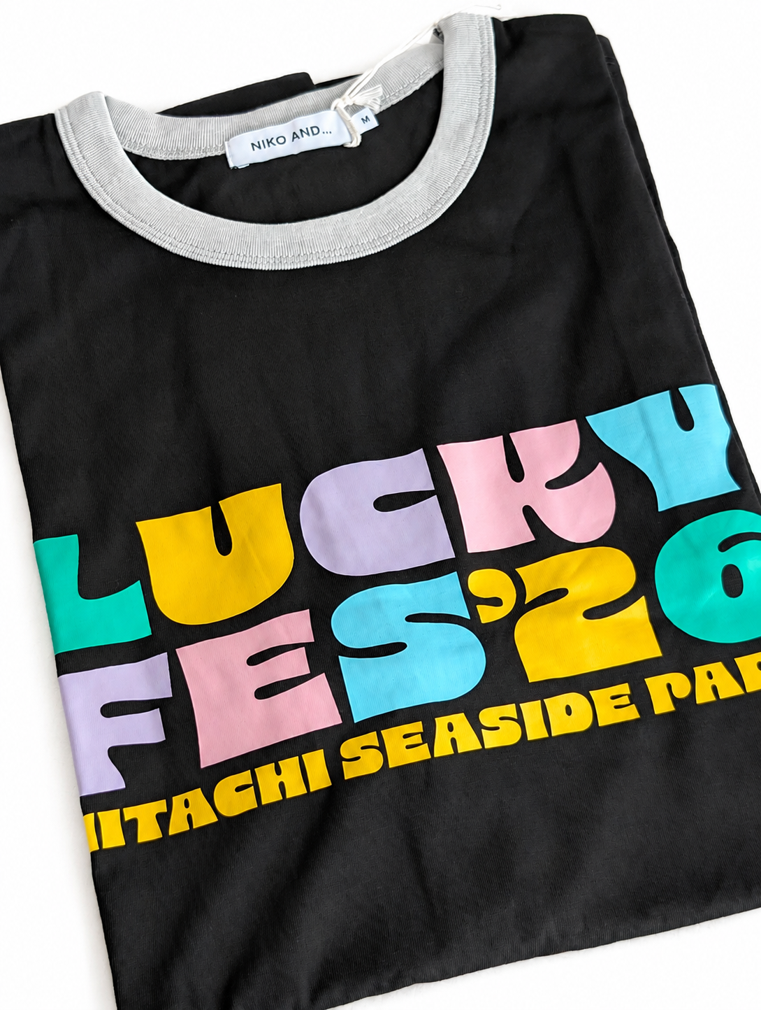 LUCKY FES &lsquo;26 HITACHI SEASIDE PARK とパステルカラーでプリントされた黒いTシャツ