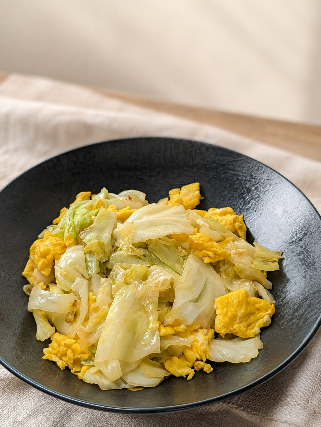 黒い皿に盛られたキャベツと卵の炒め物