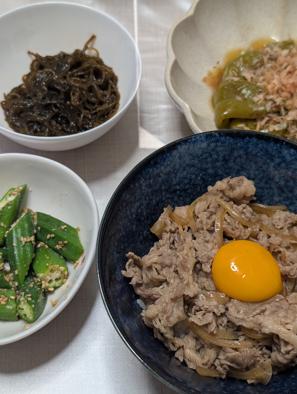 卵黄をのせた牛丼と、もずく、オクラのごま和え、ピーマンのおかか和え