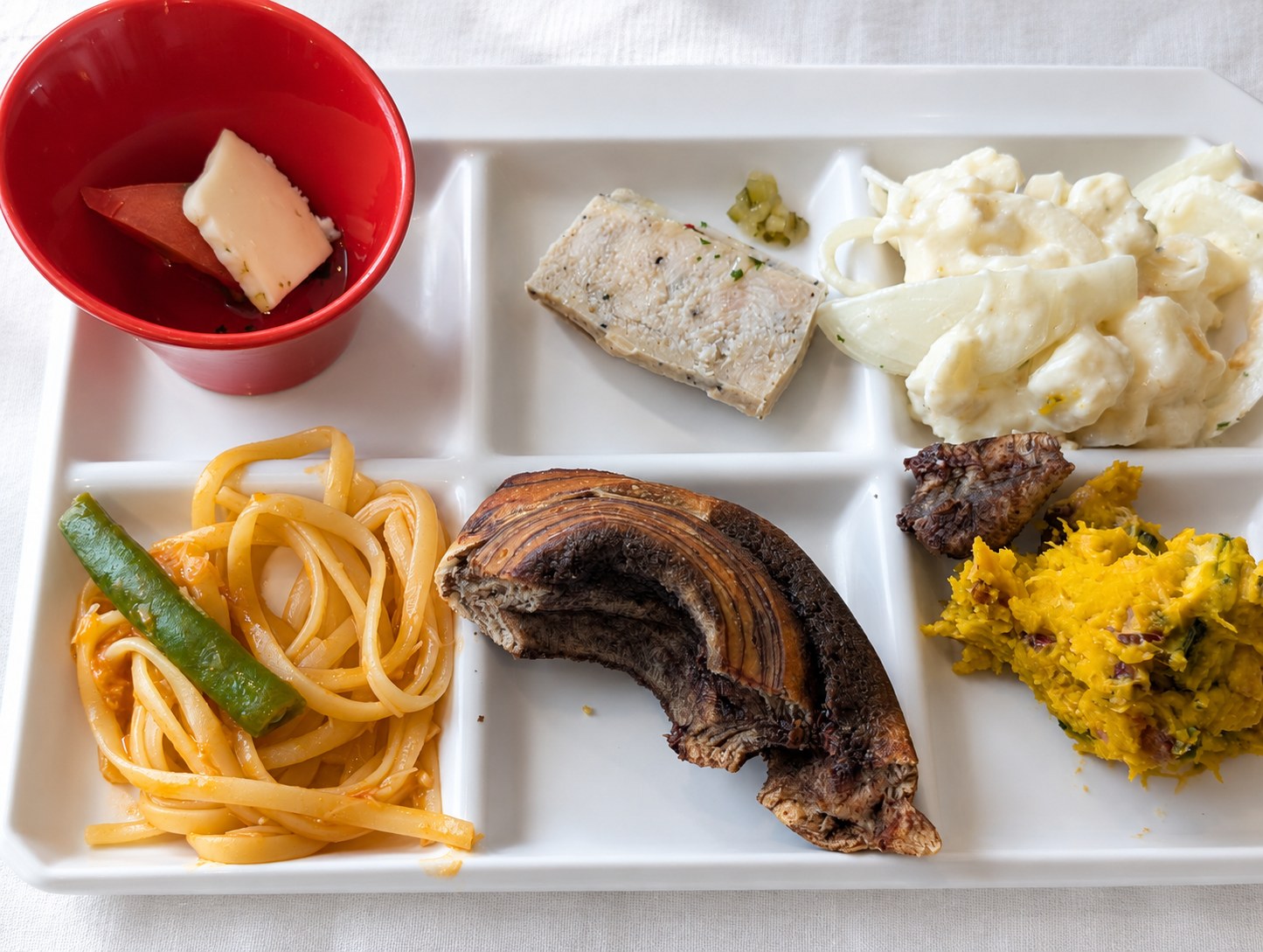 仕切り皿に取ったチーズとトマト、テリーヌ、ポテトサラダ、ナポリタン、パン、かぼちゃサラダ