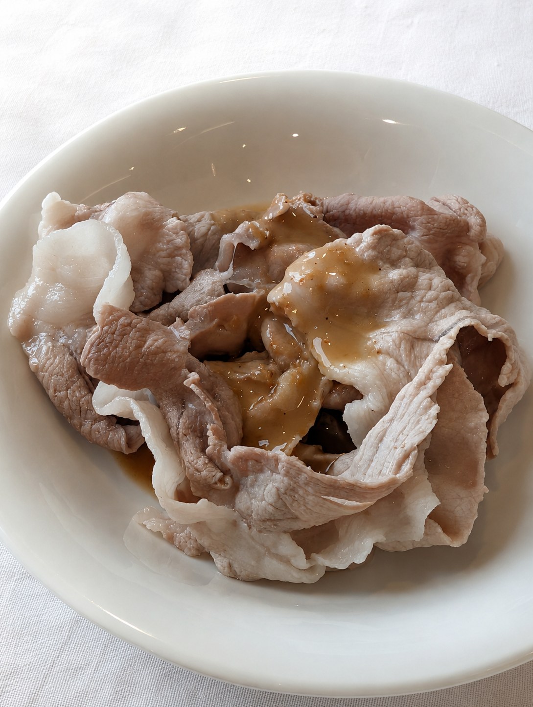 湯通しした豚の薄切り肉にごまだれをかけたしゃぶしゃぶ