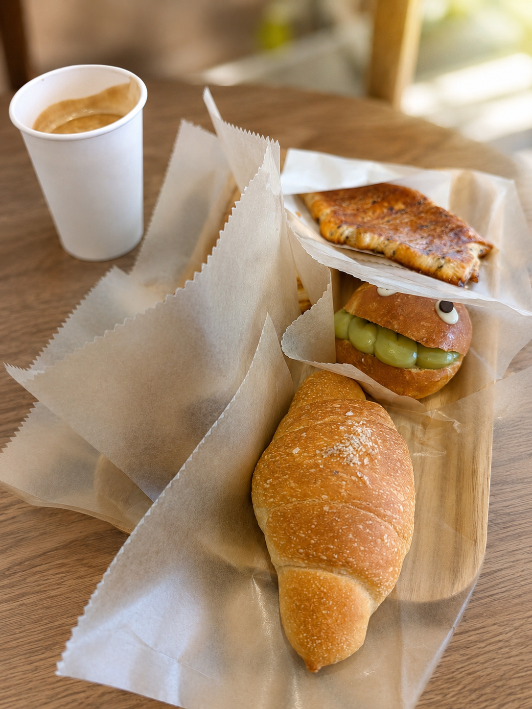 屋外のテーブルに広げた塩パン、枝豆のバンズ、ホットサンドとコーヒー