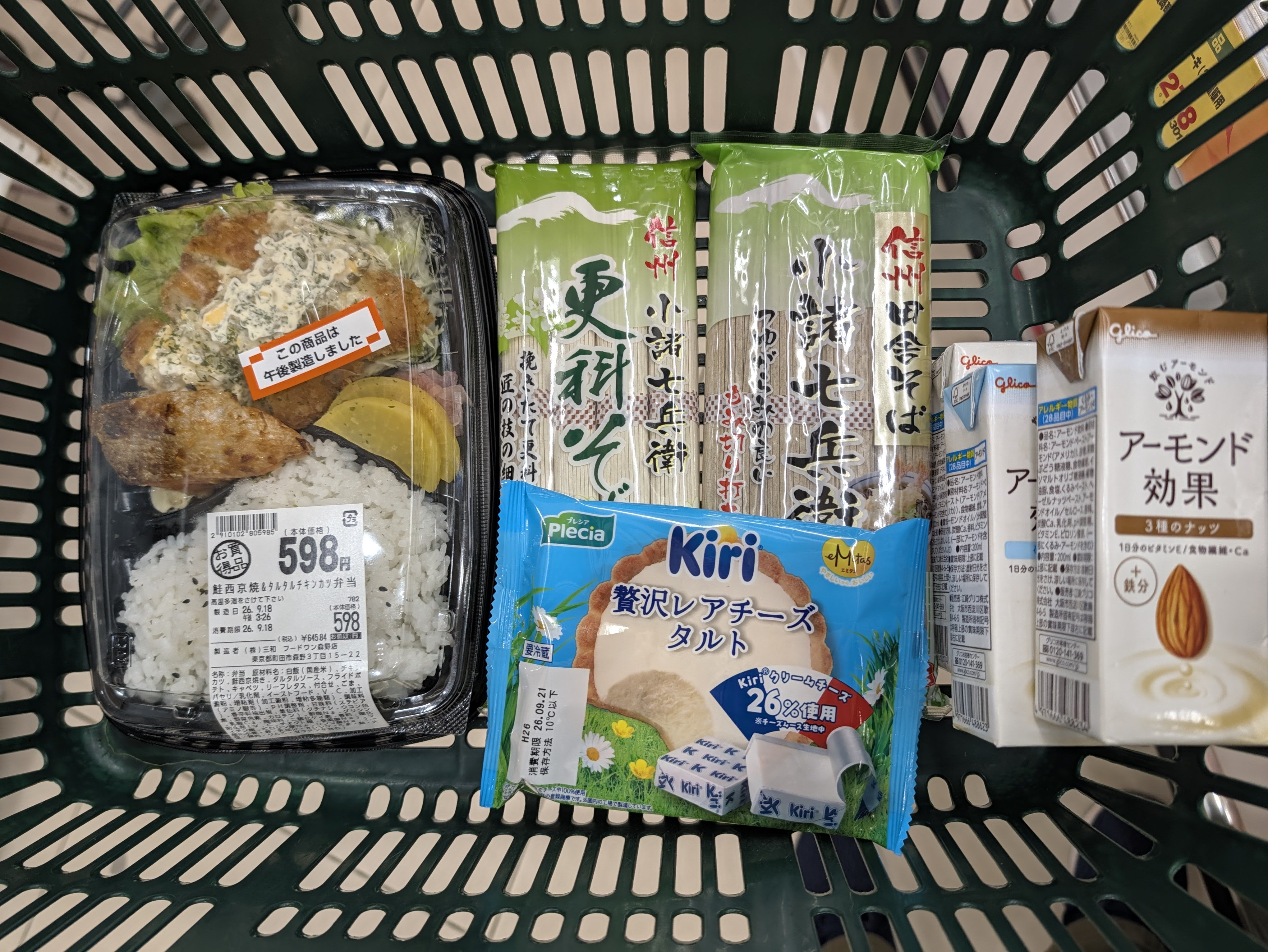 買い物かごに入った自分用の弁当とアーモンド効果、妻用のそばとKiriのレアチーズタルト
