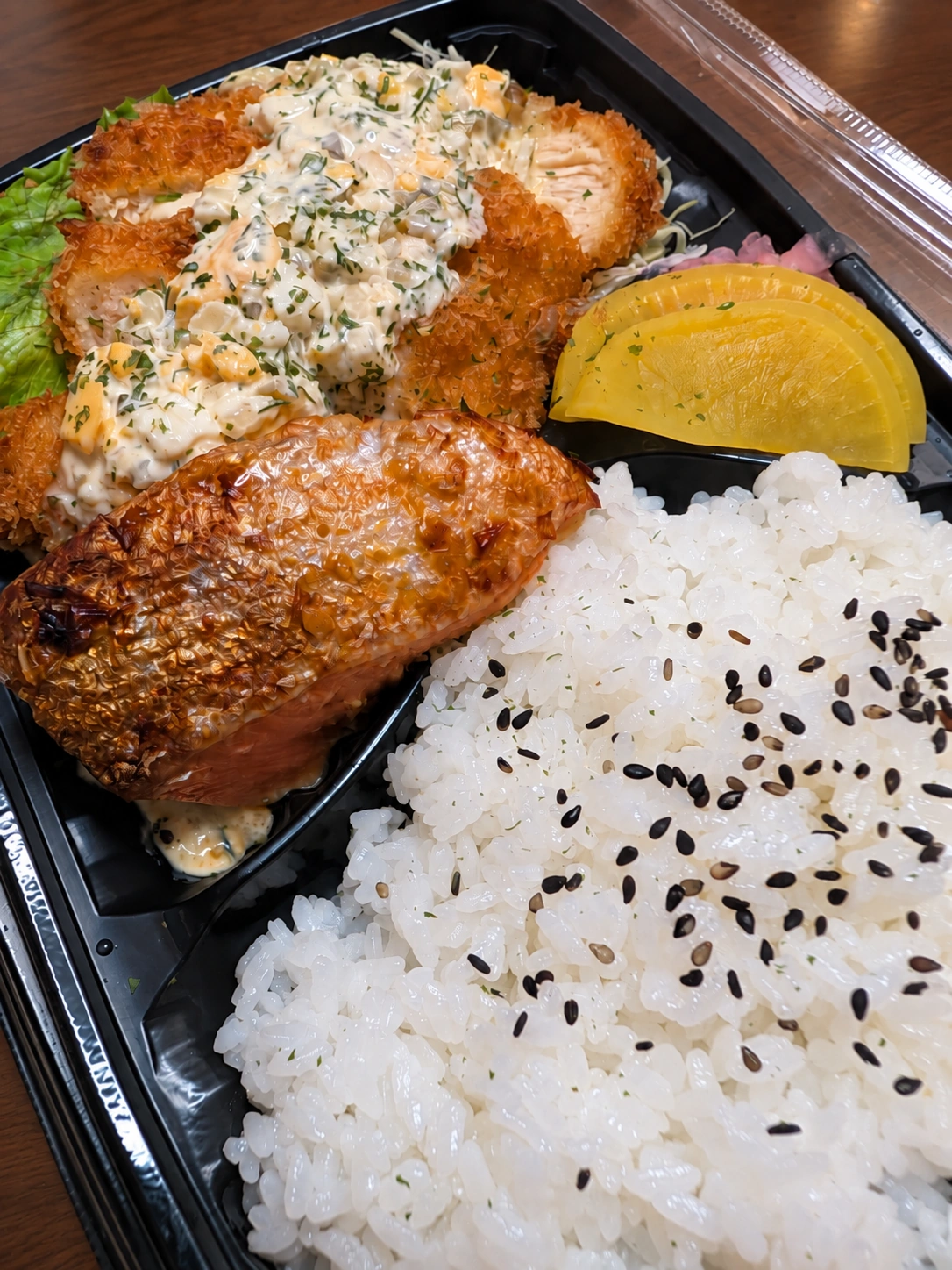 鮭西京焼、タルタルソースのかかったチキンカツ、ご飯と漬物が入った弁当
