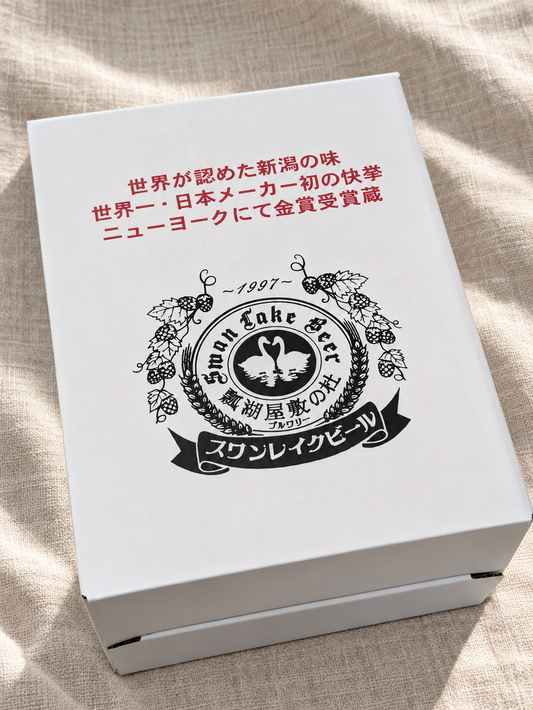 スワンレイクビールの白いギフト箱(下の布はAIで加工)
