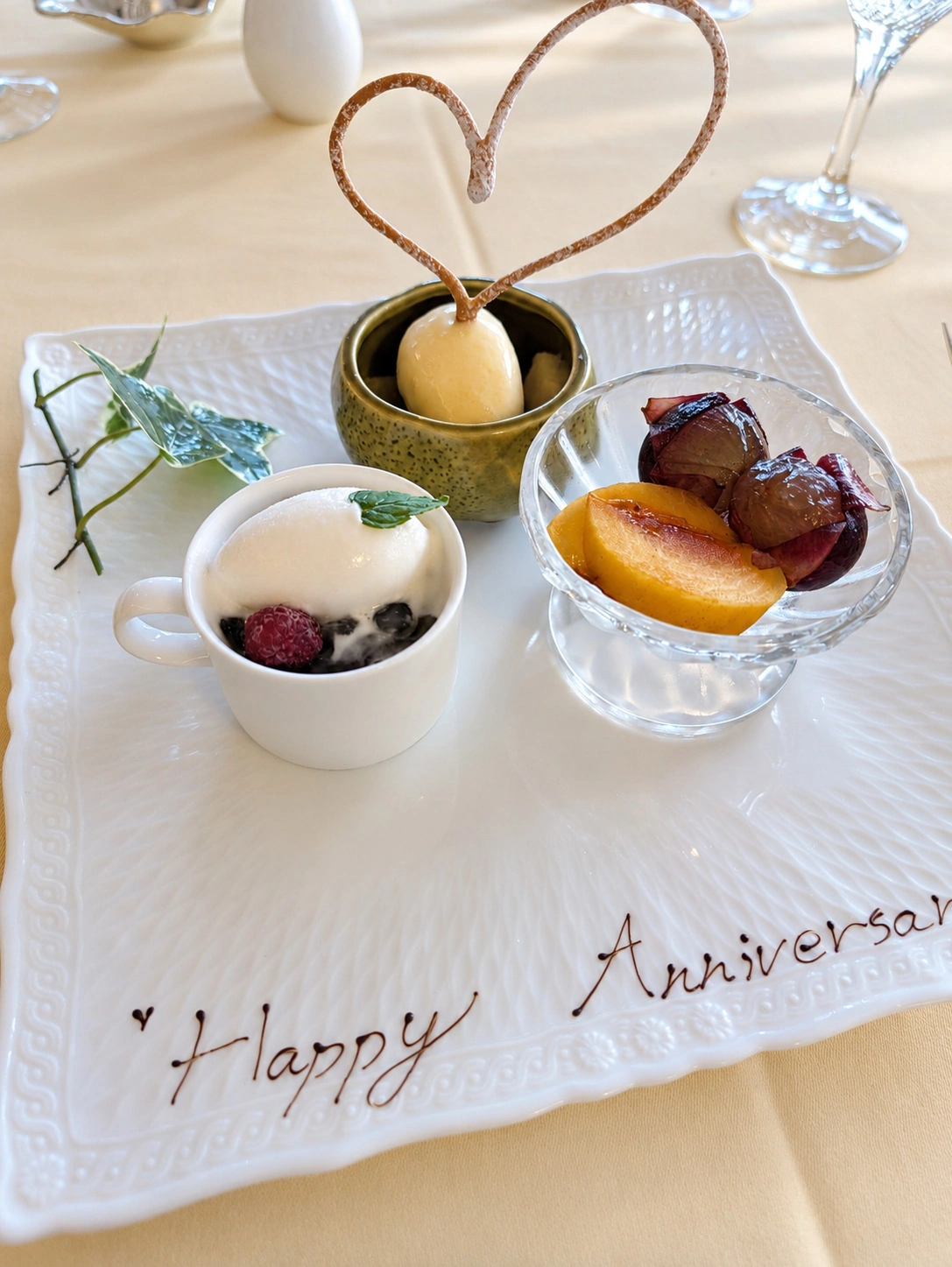 ぜんざいを含むデザートとハートの飾り、「Happy Anniversary」の文字を添えた記念日プレート(背景などはAIで加工)