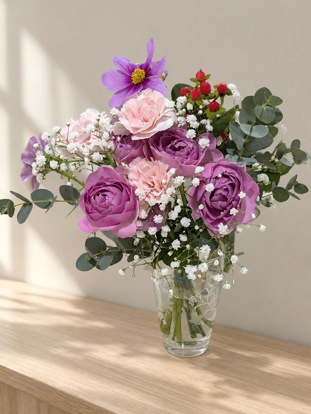 紫とピンクの花束を透明の花瓶に生けた様子（背景などはAIで加工）