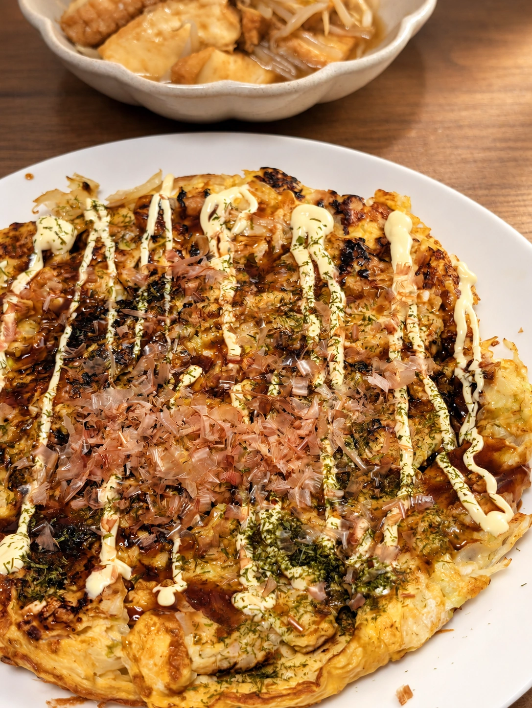 ソースやかつお節のかかったキャベツと卵の焼き物(卓上と明るさをAIで加工)
