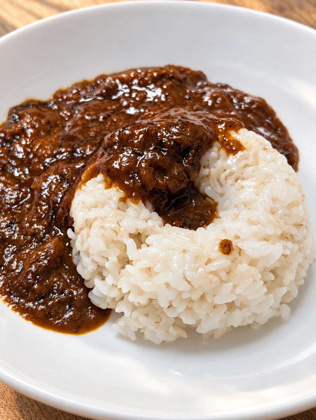 白い皿に盛ったレトルトカレーとライス(卓上・光・細部をAIで加工)