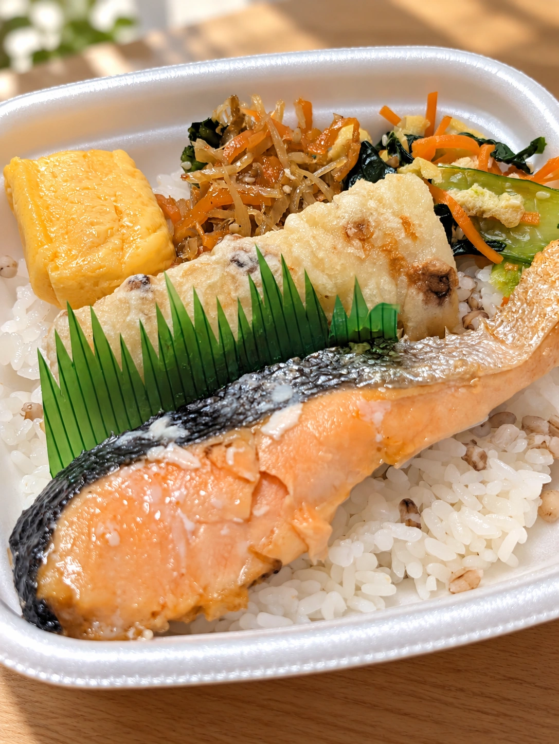 ほっともっとのもちミニしゃけ弁当。鮭、もち麦ごはん、ちくわ天、卵焼きと副菜(背景・光・細部をAIで加工)