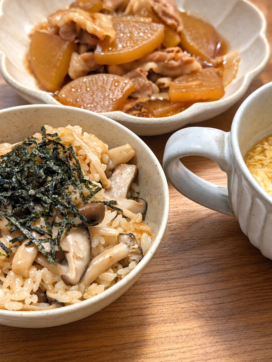 刻み海苔がたっぷりの炊き込みご飯と大根・豚肉の煮物、たまごスープ（背景・光・細部をAIで加工）